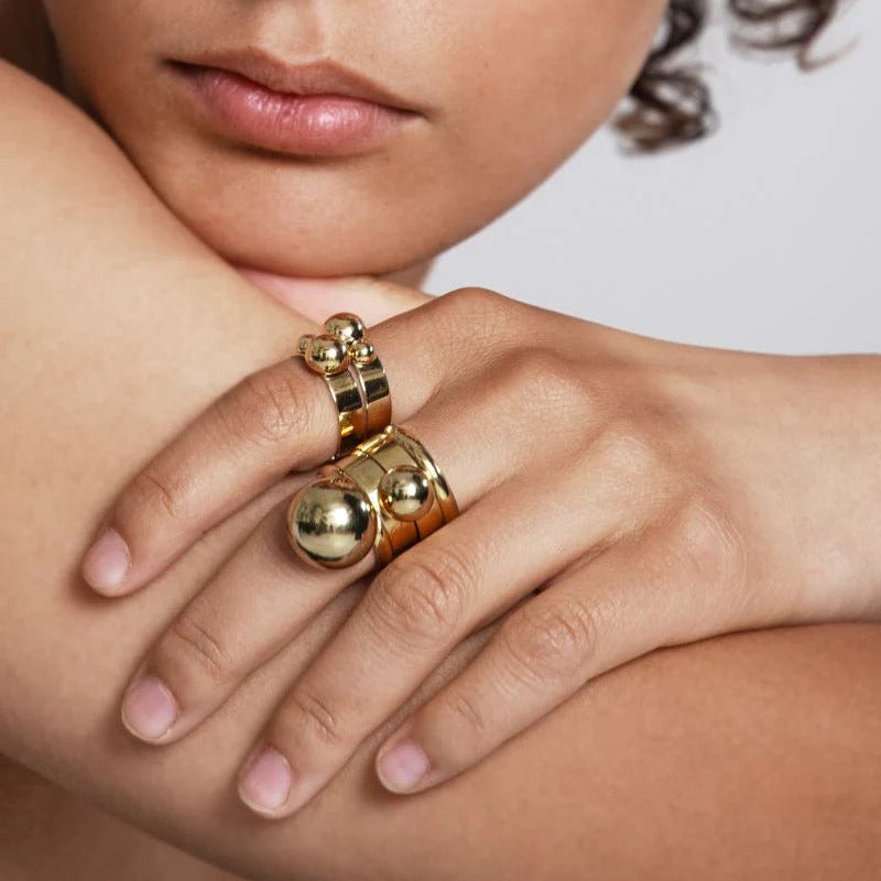 Close-up of a person wearing a gold ring on a neutral background