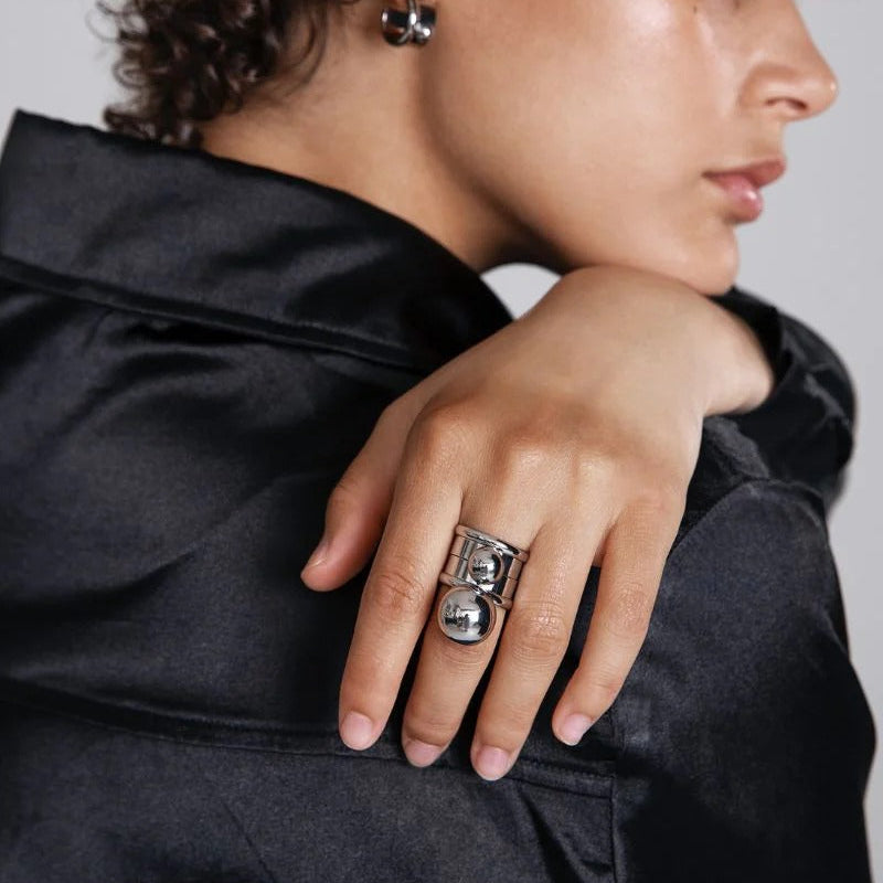 Person wearing a black jacket with a close-up of their hand and jewelry.