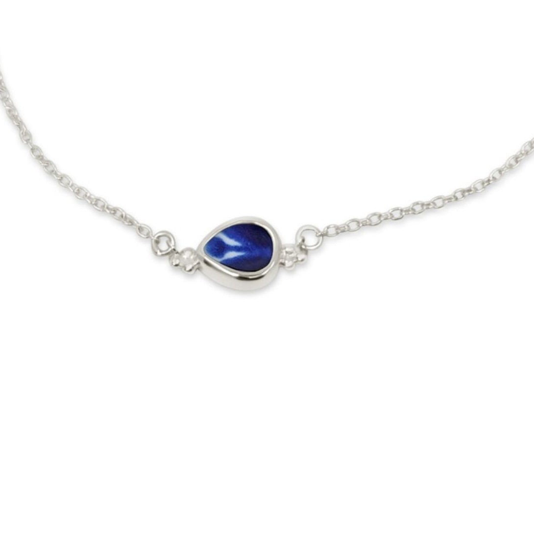 A delicate silver chain necklace featuring a central teardrop-shaped blue gemstone in a polished silver bezel setting, shown against a plain white background.