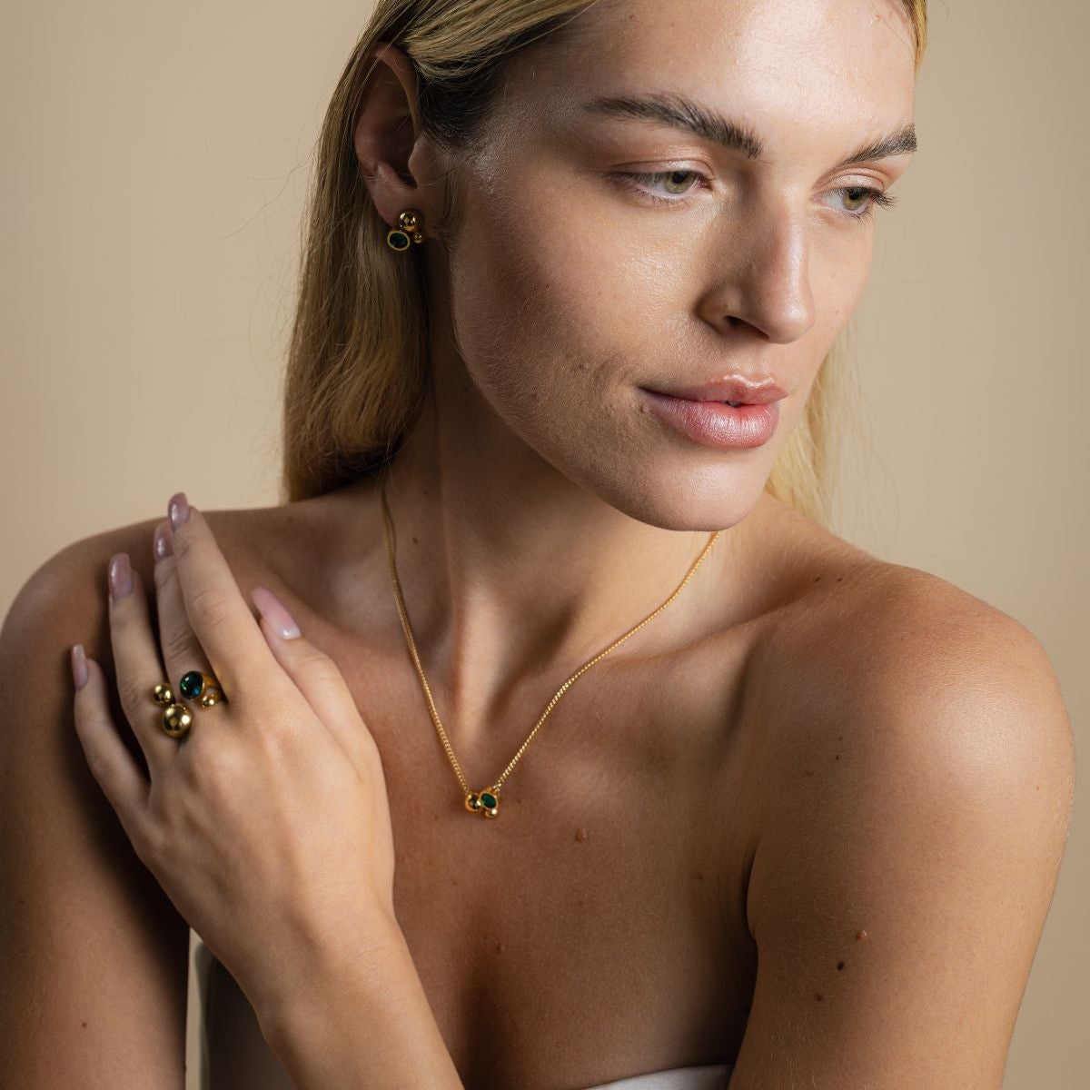 Woman wearing gold jewelry against a beige background